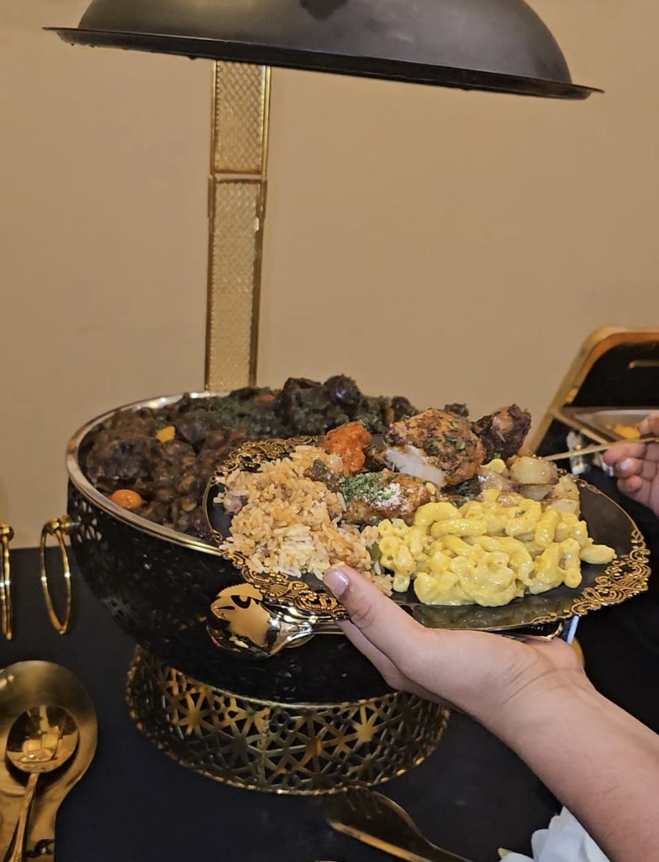 Loaded catering plate with jerk oxtail, rice and peas, and mac and cheese on a gold-rimmed charger