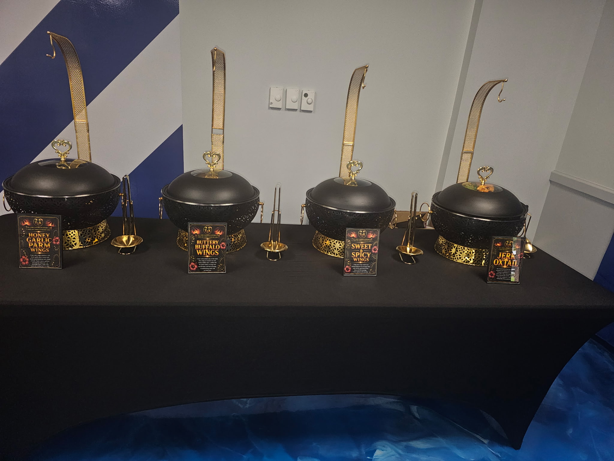 Black and gold chafing dishes with T&K menu cards — wings and oxtail station