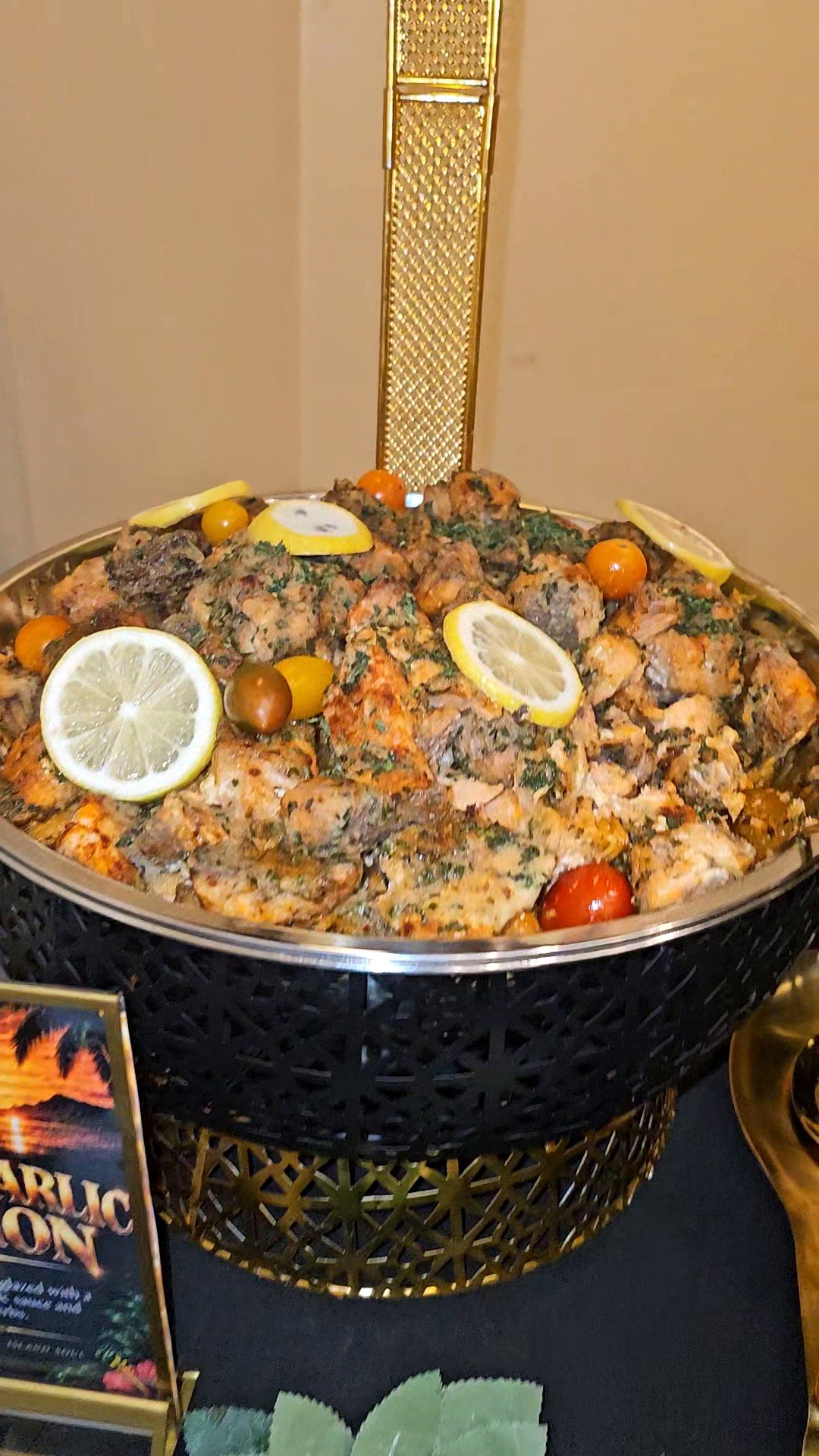 Garlic butter salmon with lemon slices and cherry tomatoes in a gold chafing dish