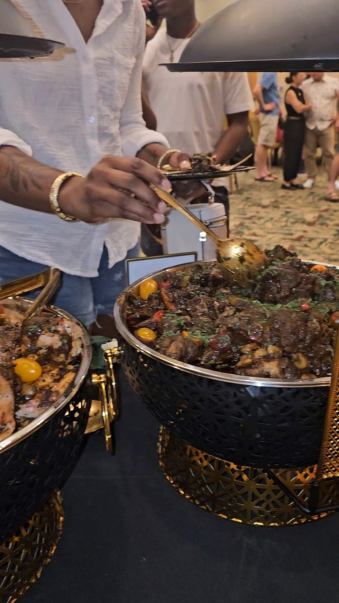 Server plating braised jerk oxtail from gold chafing dishes for guests