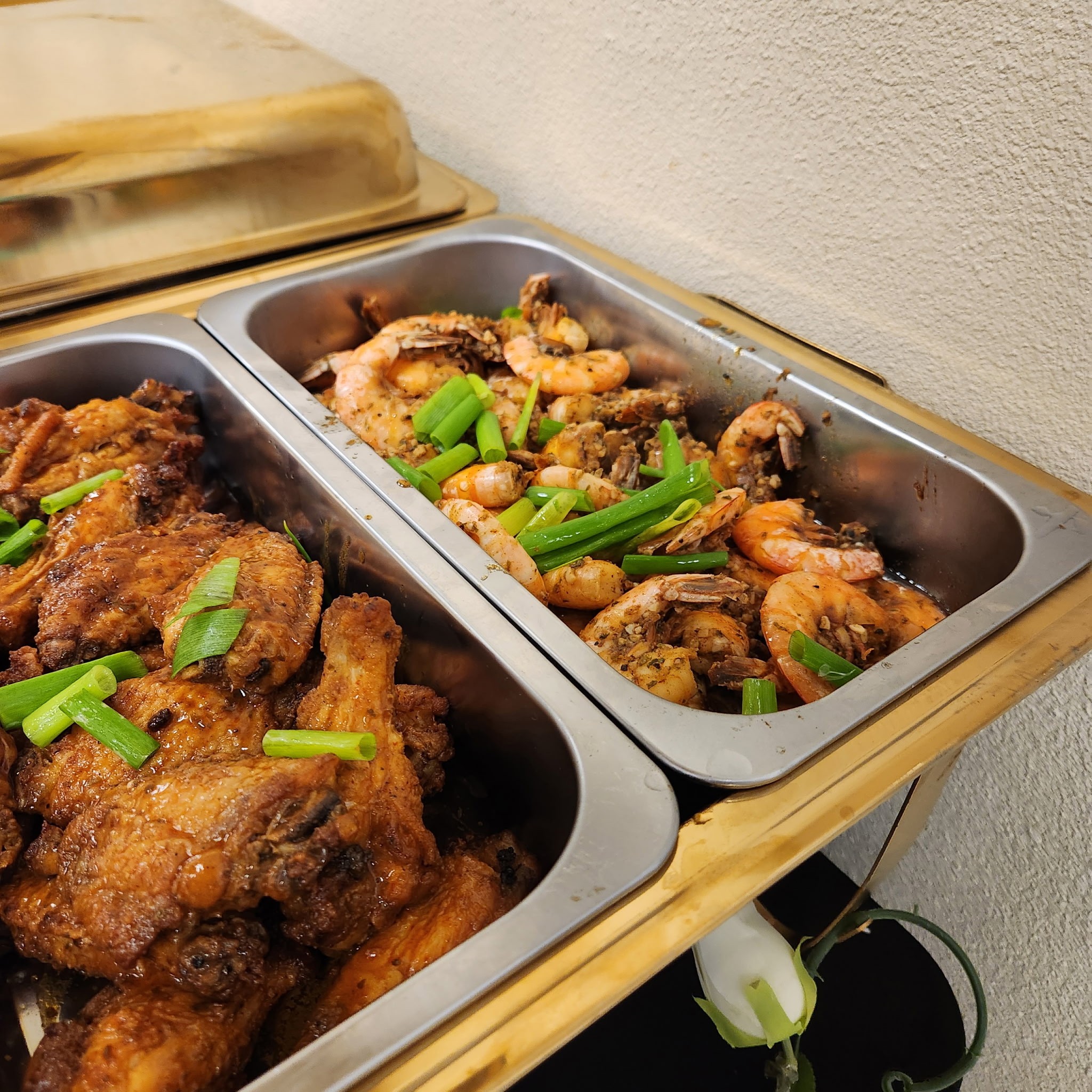 Jerk wings and seasoned shrimp in gold chafing dishes