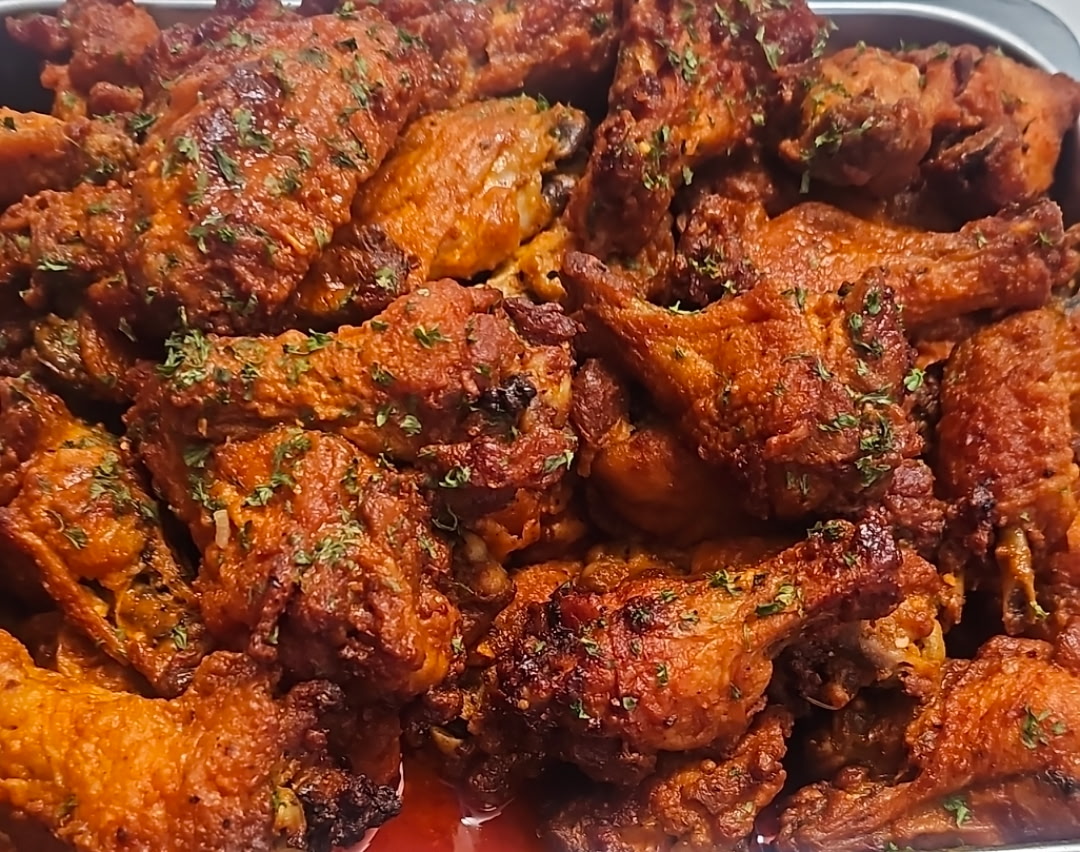 Tray of crispy saucy wings dusted with parsley